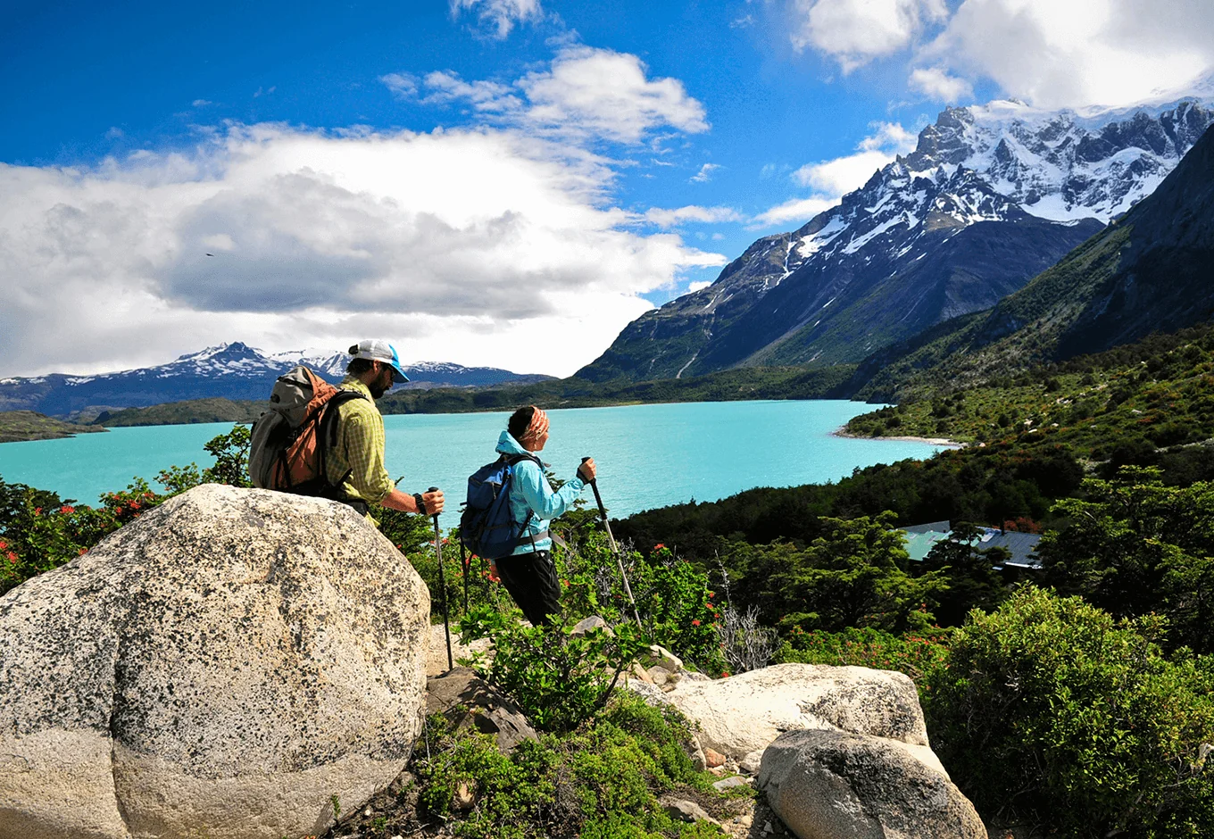Hikers overlooking turquoise glacial lake in Patagonia with snow-capped mountains
